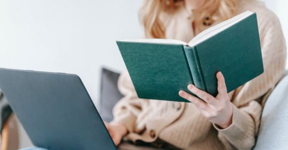 Job Search Strategies - Crop unrecognizable female checking planner while freelancing with netbook on blurred background in daylight