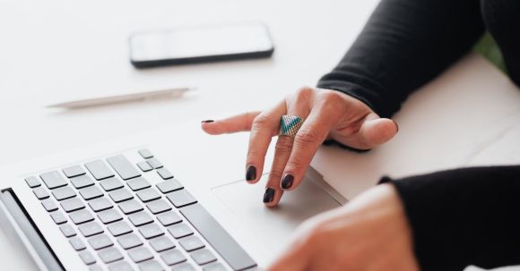 Online Presence Strategies - Crop female using touchpad on laptop in office