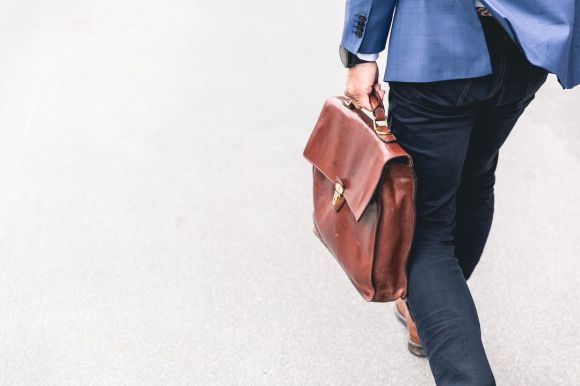 Job - person walking holding brown leather bag