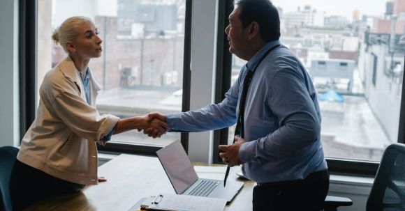 Interview Success - Young woman shaking hands with boss after business presentation