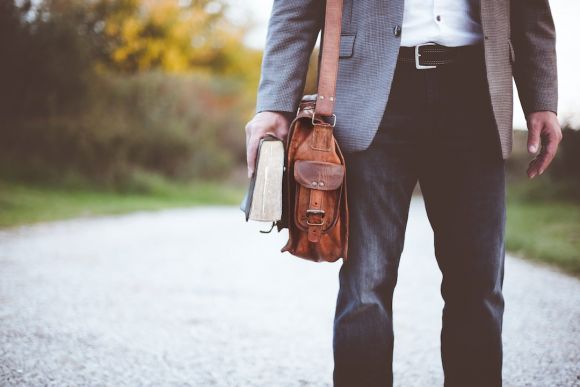 Job - man holding book on road during daytime