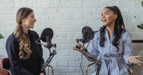 Remote Interviews. - Smiling African American female guest gesticulating while having interview with journalist sitting near mic